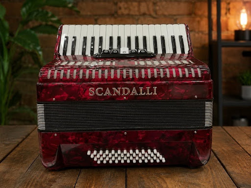 Acordeon vermelho Scandalli sobre mesa de madeira