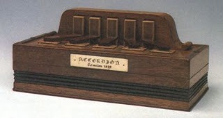 Instrumento antigo de madeira semelhante a uma sanfona primitiva, com teclas retangulares