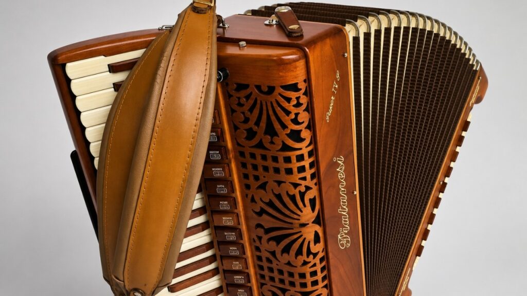 Detalhe de um acordeon antigo de madeira, com fole e grade decorativa entalhada